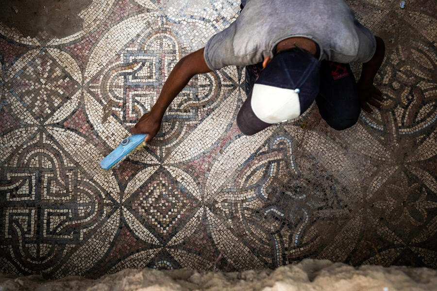 Un palestino barre el polvo de partes de un piso de mosaico de la era bizantina descubierto por un granjero en Bureij, en el centro de la Franja de Gaza | Septiembre 5, 2022 (Foto: Fatima Shbair / AP)
