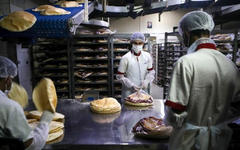 Empleados, con equipo de protección personal, empacan pan en una panadería en la capital libanesa de Beirut. (PATRICK BAZ / AFP)