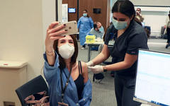 Una mujer toma una foto con su teléfono móvil mientras recibe la vacuna Pfizer-BioNTech contra COVID-19 en el centro médico de la Universidad Americana de Beirut el 14 de febrero de 2021. Foto: Reuters.