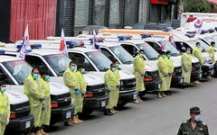 Personal de salud usa el equipo de protección cerca de las ambulancias, como parte de la preparación para ayudar a combatir el brote de la enfermedad por coronavirus. (AFP)