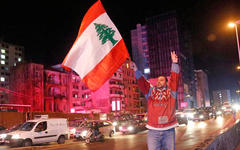 Un manifestante antigubernamental muestra el signo de la victoria y ondea una bandera libanesa, en Beirut, Líbano. AP.