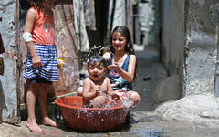 Niños palestinos se refrescan durante una ola de calor en el campo de refugiados de Bureij, en la Franja de Gaza, en mayo de 2020. Foto: AFP.