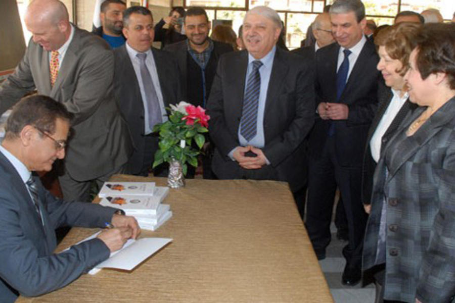 Embajador Adnan Mansour firmando copias durante la presentación.