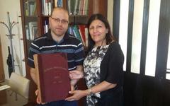 Alicia Daher haciendo entrega de un libro del CSLBA al Padre Youssef Moukharzel